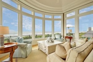 Large sitting room with giant windows showing a beach view.