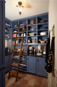 Blue kitchen cabinets with a tall wooden ladder to access the top shelves.