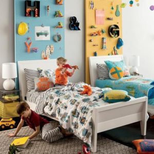 Twin beds in a kids room with peg boards used for storage on the walls behind them