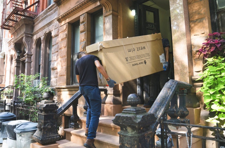 Movers moving rental furniture into a home in the city