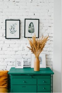 Bed side table painted green with white brick wall behind it.